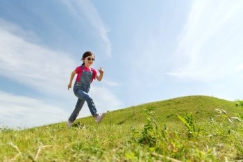 summer, childhood, leisure and people concept - happy little girl running on green summer field