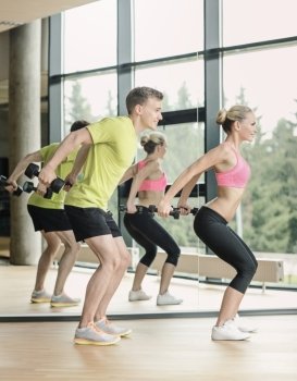 sport, fitness, lifestyle and people concept - smiling man and woman with dumbbells exercising in gym