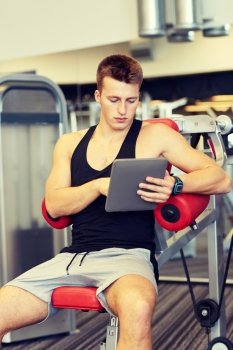 sport, bodybuilding, lifestyle, technology and people concept - young man with tablet pc computer in gym