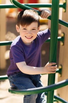 summer, childhood, leisure and people concept - happy little boy on children playground climbing frame