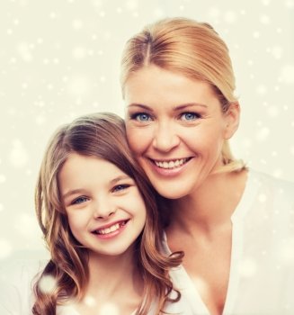 family, childhood, motherhood, people and happiness concept - smiling mother and little girl over snowflakes background