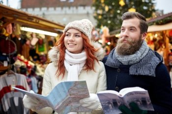 holidays, winter, christmas, tourism and people concept - happy couple in warm clothes with map and city guide in old town