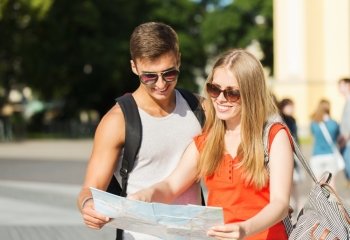 travel, tourism, summer vacation and people concept - smiling couple with map and backpack looking for location in city