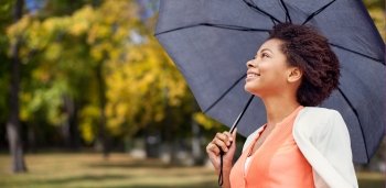 business, weather, season, fall and people concept - young smiling african american woman with umbrella over autumn park background