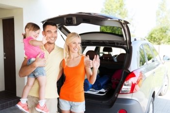 transport, leisure, road trip and people concept - happy family with little girl sitting on trunk of hatchback car and waving hands at home parking space