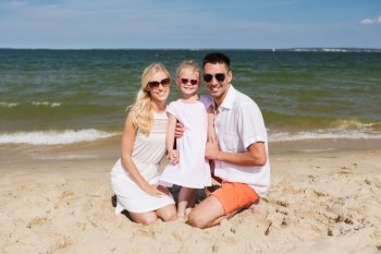 travel, vacation, adoption and people concept - happy family with little girl in sunglasses on summer beach