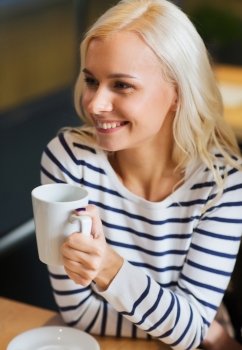 people, leisure, eating and drinking concept - happy young woman drinking tea or coffee at cafe or home