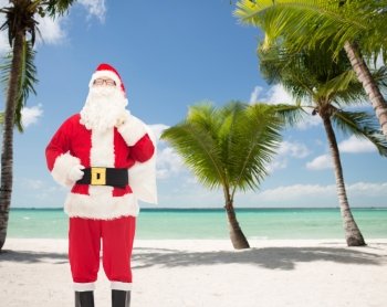 christmas, holidays, travel and people concept - man in costume of santa claus with bag over tropical beach background