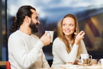 people, leisure and communication concept - happy couple meeting and drinking tea or coffee at cafe