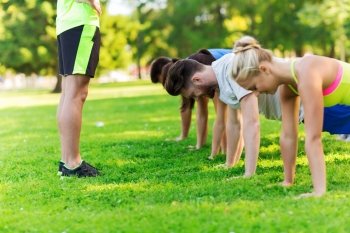 fitness, sport, friendship and healthy lifestyle concept - group of happy teenage friends or sportsmen exercising and doing push-ups at boot camp