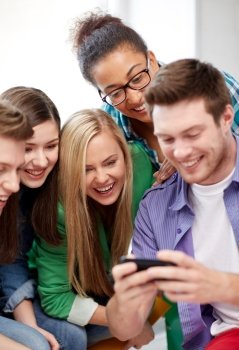 education, people, friendship, technology and learning concept - group of happy international high school students or classmates with smartphone in classroom