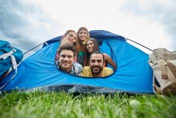 travel, tourism, hike, equipment and people concept - group of happy friends with backpacks in tent at camping
