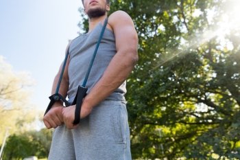 fitness, sport, exercising, training and lifestyle concept - close up of young man exercising with expander in summer park
