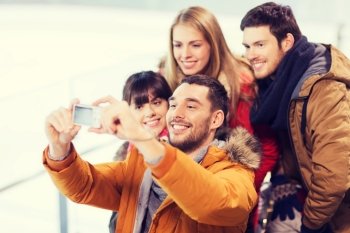 people, friendship, technology and leisure concept - happy friends taking selfie with digital camera on skating rink