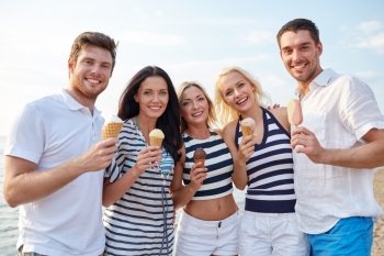 summer, holidays, sea, tourism and people concept - group of smiling friends eating ice cream on beach