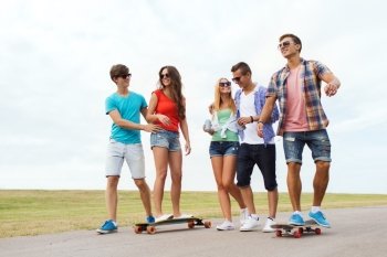 people, leisure and sport concept - group of happy teenage friends with longboards and drinks outdoors