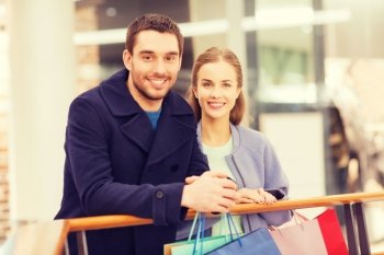 sale, consumerism and people concept - happy young couple with shopping bags in mall