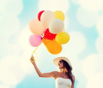 happiness, summer, holidays and people concept - smiling young woman wearing sunglasses with balloons over blue lights background