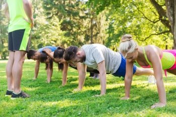 fitness, sport, friendship and healthy lifestyle concept - group of happy teenage friends or sportsmen exercising and doing push-ups at boot camp