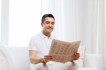 leisure, information, people and mass media concept - happy man reading newspaper at home