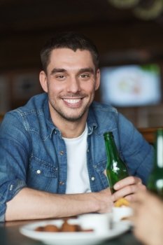 people, leisure and bachelor party concept - happy young man drinking beer at bar or pub