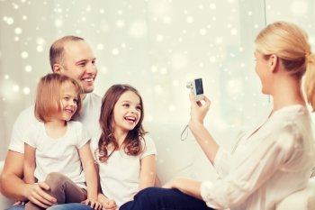 family, home, technology and people - happy family with camera taking picture over snowflakes background