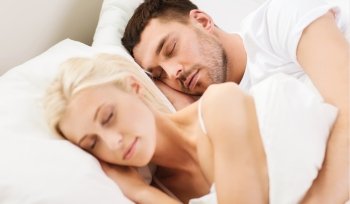 people, family, bedtime and happiness concept - happy couple sleeping and hugging in bed at home
