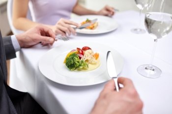 restaurant, food, people, date and holiday concept - close up of couple eating appetizers at restaurant