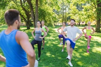 fitness, sport, friendship and healthy lifestyle concept - group of happy teenage friends or sportsmen exercising and raising legs at boot camp