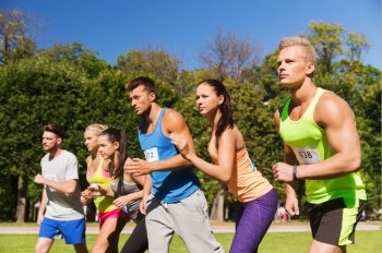 fitness, sport, race and healthy lifestyle concept - group of teenage friends or sportsmen with badge numbers on start of running marathon outdoors