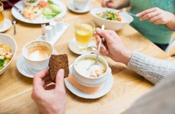 people, leisure and food concept - close up man eating cream salmon soup with rye bread for dinner at restaurant or home