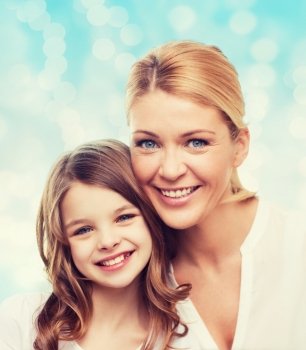 family, childhood, happiness and people - smiling mother and little girl over blue lights background