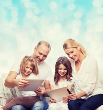 family, holidays, technology and people - smiling mother, father and little girls with tablet pc computers over blue lights background