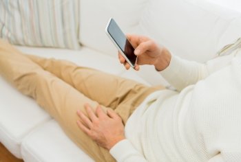 technology, people, lifestyle and communication concept - close up of man with smartphone lying on sofa at home