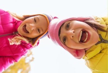 childhood, leisure, friendship and people concept - happy laughing girls faces outdoors