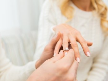 love, couple, relationship and holidays concept - close up of man giving diamond ring to woman