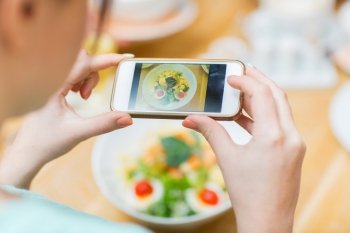 people, leisure and technology concept - close up of woman hands with smartphone taking picture of food at restaurant