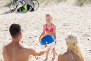 family, summer vacation, adoption and people concept - close up of happy man, woman and little girl playing with inflatable ball on beach