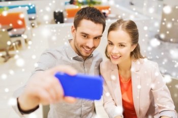 technology and people concept - happy couple taking selfie with smartphone in mall or cafe with snow effect. happy couple taking selfie with smartphone in cafe