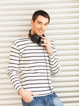 man in casual clothes with headphones leaning to wall