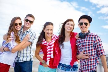 summer holidays and teenage concept - group of smiling teenagers hanging outside. group of smiling teenagers hanging out