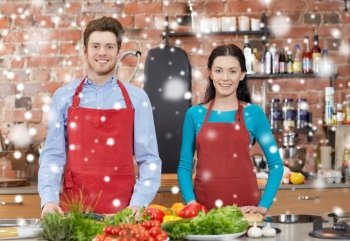 cooking class, culinary, food and people concept - happy couple in kitchen over snow effect