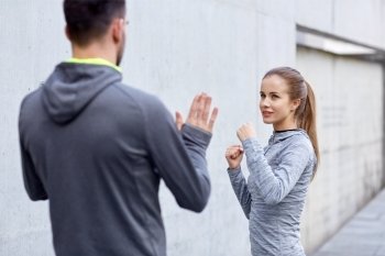 fitness, sport, martial arts, self-defense and people concept - happy woman with personal trainer working out strike outdoors