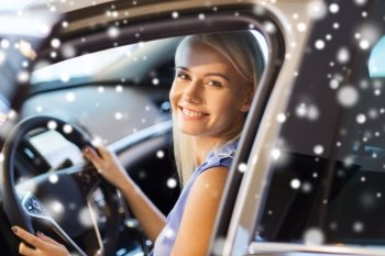 auto business, car sale, consumerism , transportation and people concept - happy woman sitting in or driving car over snow effect