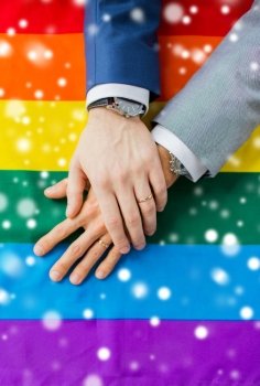 people, homosexuality, same-sex marriage, gay and love concept - close up of happy male gay couple hands over rainbow flag over snow effect