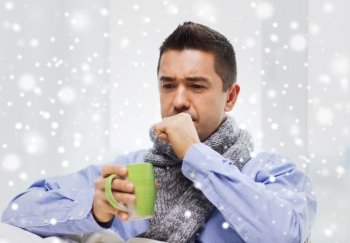 healthcare, people and medicine concept - ill man with flu coughing and drinking hot tea from cup at home over snow effect