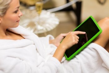 people, beauty, lifestyle, technology and relaxation concept - close up of beautiful young woman in white bath robe with tablet pc computer social networking at spa