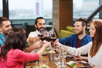 leisure, celebration, food and drinks, people and holidays concept - smiling friends having dinner and drinking red wine at restaurant
