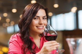 leisure, drinks, degustation, people and holidays concept - smiling woman drinking red wine at restaurant