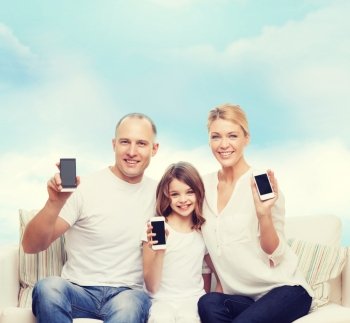 family, technology, advertisement and people concept- smiling mother, father and little girl with smartphones over blue sky background